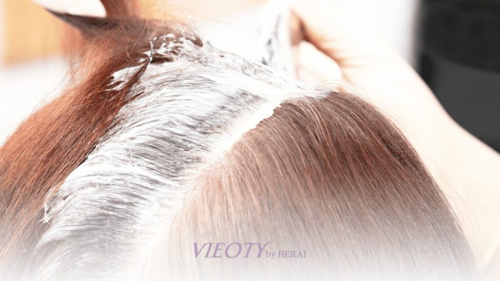 美容師がお客様の頭皮を保護しながら丁寧に白髪染めを塗布している様子