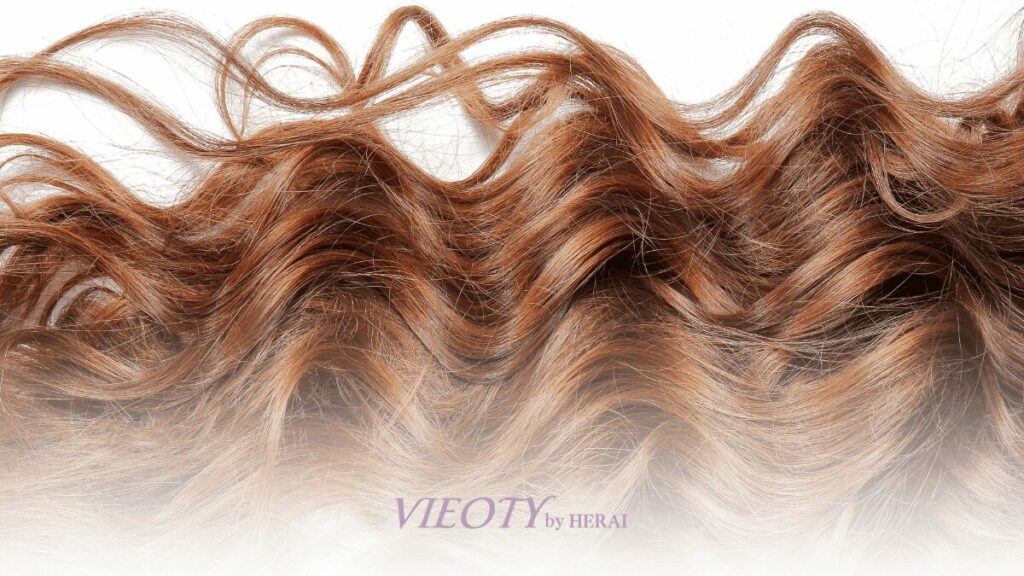 鏡の前で自分の新しいくせ毛スタイルに微笑む、自信に満ちた50代の女性