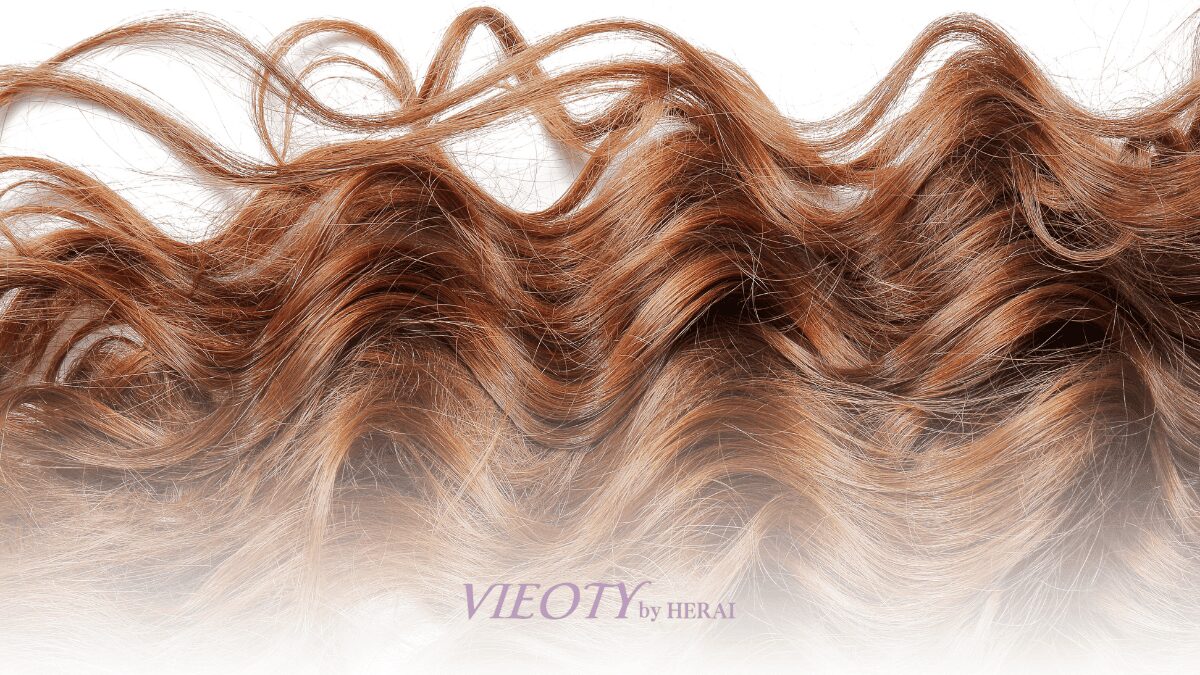 鏡の前で自分の新しいくせ毛スタイルに微笑む、自信に満ちた50代の女性