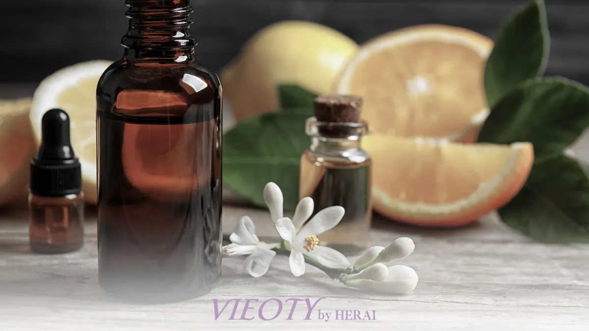 朝陽が差し込む実験室のアランビック蒸留器と、ビターオレンジの花、VIEOTYのボトル